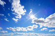 Bright, summer, sultry sun against background blue sky and white clouds.