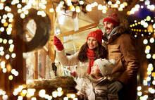 Family, Winter Holidays And Celebration Concept - Happy Mother, Father And Little Daughter At Christmas Market On Town Hall Square In Tallinn, Estonia