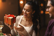 © Syda Productions - holidays, party and celebration concept - happy smiling woman with gift box on christmas dinner at home