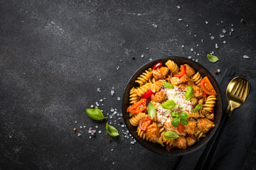 Wall Mural - Pasta chicken with vegetables. Served with parmesan. Top view at black table.