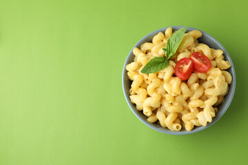 Plate with macaroni and cheese on green background