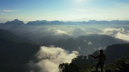 Wall Mural - Backpacker standing on sunrise viewpoint at Ja Bo village, Mae hong son province, Thailand.