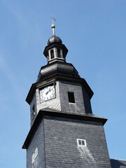 verschieferter kirchturm mit kirchturmuhr