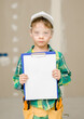 © Ermolaev Alexandr - Young boy dressed like a worker shows clipboard with empty list