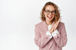 © Cookie Studio - Image of businesswoman in glasses and suit clap hands, smiling and laughing pleased, relish something good, standing over white background