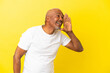 © luismolinero - Cuban Senior isolated on yellow background shouting with mouth wide open to the side