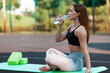 A break in exercise. Redheaded girl drinking water. Yoga class outside..