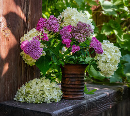 Wall Mural - Still life with a bouquet of white and lilac flowers in a ceramic vase. Blooming hydrangea. Vintage.