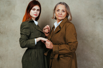 young and old woman are standing next to each other in a coat posing