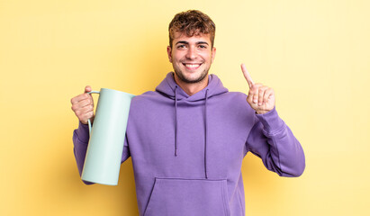Wall Mural - young handsome man smiling and looking friendly, showing number one. thermos concept