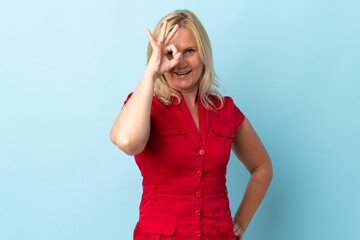 Wall Mural - Middle age woman isolated on blue background showing ok sign with fingers