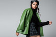 © LIGHTFIELD STUDIOS - stylish woman in green leather jacket, checkered skirt and beret posing isolated on grey