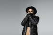 © LIGHTFIELD STUDIOS - young woman in fedora hat and trendy leather jacket covering face with hands isolated on grey