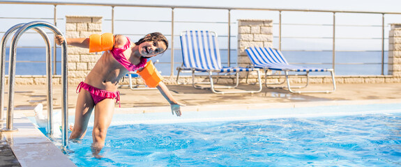 Pretty little girl swimming in outdoor pool and have a fun