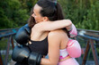 © luisrojasstock - Young caucasian women getting a hug after practicing boxing on a bridge at sunset