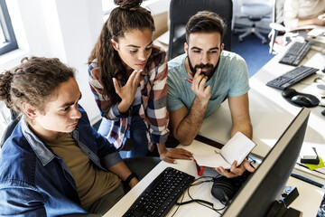 Group of  programmers working and disccuss about  new project at the office.	
