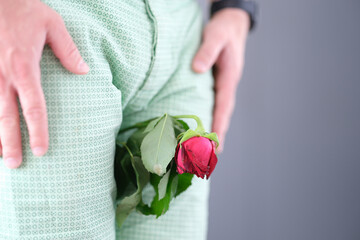 Withered rose flower sandwiched between man legs closeup