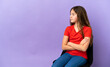 © luismolinero - Little caucasian girl sitting on a chair isolated on purple background keeping the arms crossed