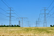 © elxeneize - Electricity pylons and power lines with wind turbines in the back in Germany