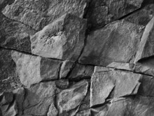 Rock Texture. Cracked Mountain Surface. Close-up. It Looks Like A Stone Wall. Black White Grunge Background For Design.