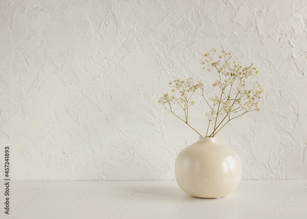 Modern beige ceramic vase with dry flowers on white table near a ...