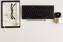 White Office Desk Top View Template With Copy Space.Minimal Workspace With Keyboard, Glasses, Notebooks. Black. White. Gold Color. Workplace Of Modern Style .