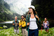 © NDABCREATIVITY - Group of smiling friends hiking with backpacks outdoors. Travel, tourism, hike and people concept.