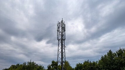 3G, 4G, 5G. Mobile phone base station Tower. Development of communication system in npn-urban forest area with dark stormy grey sky background. High quality photo