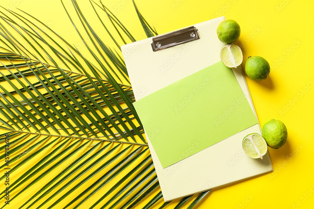 Composition with blank card, clipboard, limes and palm leaves on color background
