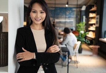 Wall Mural - Successful smiling asian businesswoman standing in creative office and looking at camera at modern office