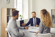 © Studio Romantic - Clients talking to bank manager. Young married couple meeting with realtor, real estate agent or mortgage advisor. Man and woman sitting at office desk and having discussion with insurance broker