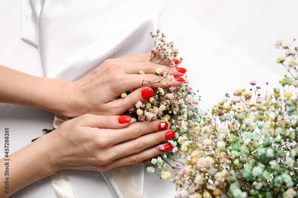 Woman with beautiful manicure holding flowers on white background