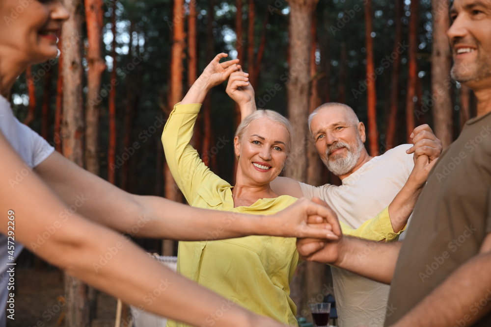 Mature people dancing at barbecue party outdoors