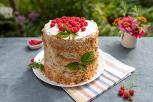 Raspberry Homemade Cake On Table In Garden On Sunny Summer Morning, Small Bouquet Of Garden Flowers In Vase In Background. Summer Vacation Concept