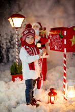 Little Child, Toddler Boy, Sending Letter To Santa In Christmas Mailbox, Christmas Decoration Around Him, Outdoor Snow Shot