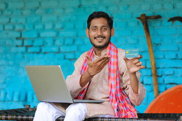 Wall Mural - Indian farmer using laptop and card at home.