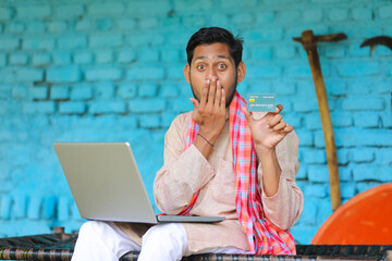 Wall Mural - Indian farmer using laptop and card at home.