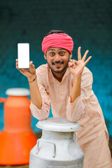 Canvas Print - Indian milkman showing smartphone screen at dairy farm.