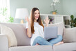 © deagreez - Portrait of attractive cheerful lucky girl sitting on divan using laptop having fun at home living room indoors
