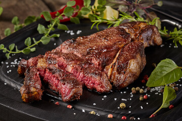 Sliced veal steak with spices and herbs on wooden background