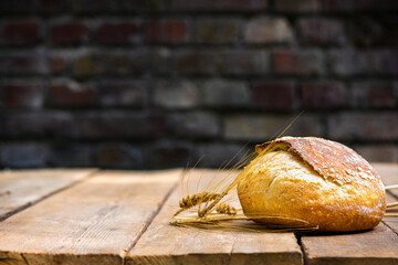 Aufkleber - Bakery background. Whole loaf of fresh crispy bread on a wooden table with ears of wheat