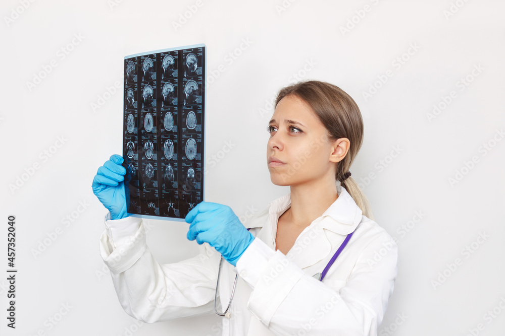 A young blonde female doctor examining MRI scan of head and brain of ...