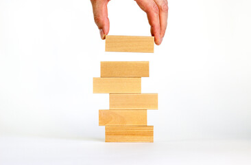 Wall Mural - Symbol of building success foundation. Businessman hand put wooden blocks on the stack of wooden blocks. Beautiful white background, copy space. Business, building success foundation concept.