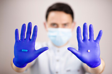 The guy in the protective mask and gloves. Pills in outstretched hands. One tablet in each hand. Medicines in hand. Doctor with medicines. Tablets to choose from.