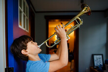 A Boy Stands In A Colorful Open Doorway Playing A Trumpet