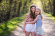 © Cavan Images - Two pretty teen girls, best friends, standing on tree lined road.
