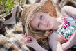 © Cavan Images - Beautiful Teen Girl with sun hat lying on a blanket outdoors.