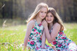 © Cavan Images - Two young teen girls in sundresses sitting on a blanket outdoors.