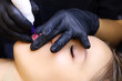 © Roman - the tattoo artist makes permanent makeup of the model's lips works with the lower lip