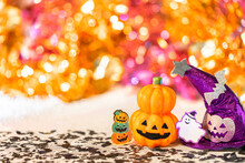 Creative Photography Depicting An Halloween Jack O Lantern Pumpkin Head And A Purple Witches Hat With Funny Ghost Smiling And Cardboard Cutout Bats Against A Colorful Background Of Bokeh Balls.